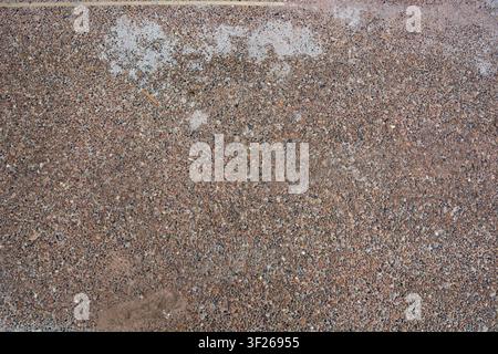Wet gravel surface shows scattered puddles. Texture blends earthy tones with natural imperfections. Ideal for background or texture use in design proj Stock Photo