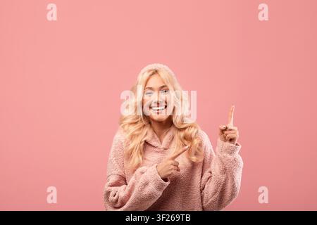 Smiling Young Woman Pointing At Something On Pink Background, Lifestyle Concept Stock Photo