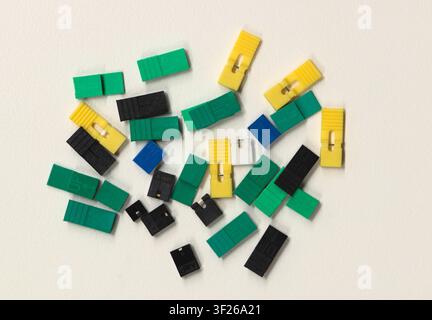 Circuit board jumper caps plastic computer components scattered loosely on white background. Stock Photo