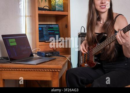 Young Musician Playing Electric Bass Guitar in Modern Home Music Room Stock Photo