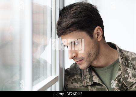 Thoughtful Male Soldier Looking Through Window, Reflection, Military Concept Stock Photo