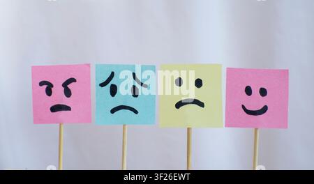 Four Emotion Face Sticky Notes on White Fabric Background Stock Photo