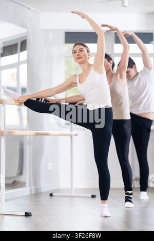 Group of dancers doing stretching at barre Stock Photo