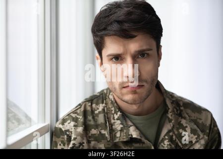 Serious Young Male Soldier In Military Uniform, Looking Confident, Indoor Setting, Healthcare Concept Stock Photo