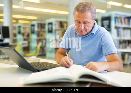 Elder male doing research on project in the city library Stock Photo