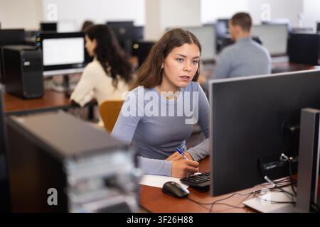 Young woman taking notes while working at computer Stock Photo