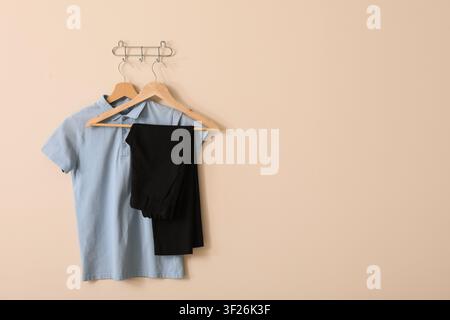 Light blue polo shirt and black trousers on wooden hangers, school uniform concept, ready for the new academic year Stock Photo
