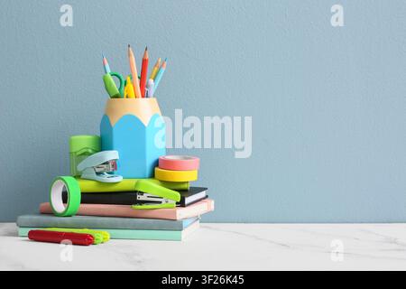 Colorful school supplies and stationery items stacked on books against a light blue background education and learning, the collection includes pencils Stock Photo