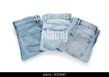 Three pairs of folded light blue denim jeans with back pockets visible, casual fashion and apparel concept, isolated on a white background Stock Photo