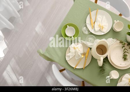 Elegant table setting with green tablecloth and golden cutlery for a festive meal or special occasion, the dining arrangement is prepared for a festiv Stock Photo