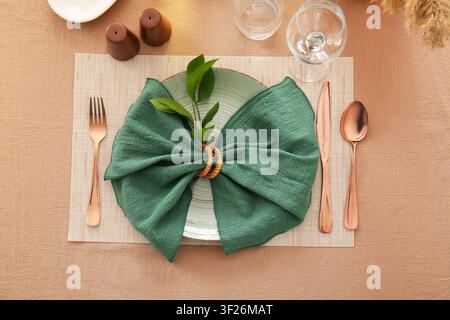 Elegant table setting with green napkin and copper cutlery on a placemat, top view for dining and hospitality concepts Stock Photo