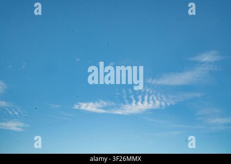 A clear blue sky with wispy, scattered cirrus clouds forming a faint, streaked pattern near the horizon. Stock Photo