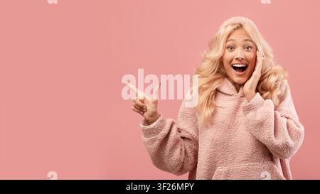 Excited Young Woman Pointing At Something Surprised, Happy Expression, Studio Setting Stock Photo