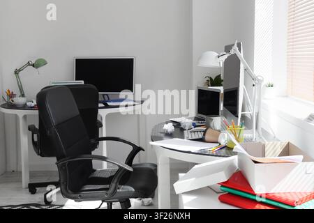 Messy home office with two desks computer monitors laptops and an ergonomic chair remote work and disorganization, disorganized Stock Photo