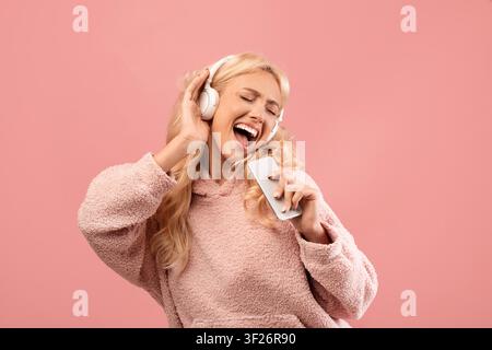 Happy Young Woman Singing With Headphones, Enjoying Music On Smartphone, Joyful Mood Stock Photo