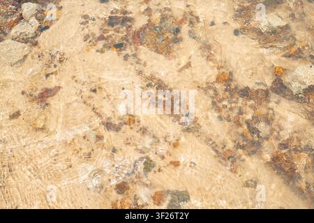 Close-up view of a textured, light brown marble surface with natural veining and mineral inclusions. Stock Photo