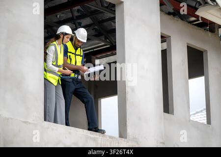 Construction managers checking clipboard on second floor balcony of unfinished residential house during daytime, concept of project management and tea Stock Photo