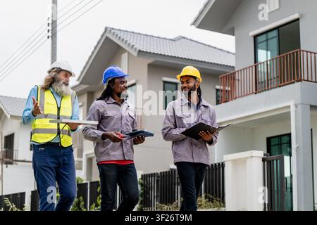 Construction engineers walking through residential development site to inspect and coordinate building progress, discussing work progress while walkin Stock Photo