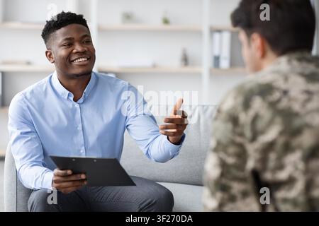 Smiling Black Male Therapist Engaging With Client In Office, Mental Health Concept Stock Photo