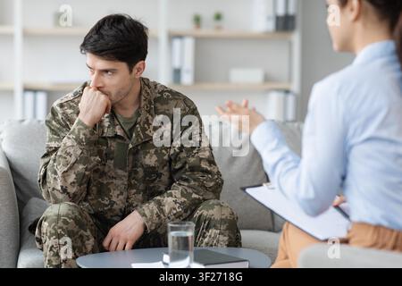 Worried Male Soldier In Military Uniform Engaging In Counseling Session, Healthcare Concept Stock Photo