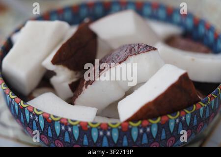 Coconut pieces in a colorful bowl on a table Stock Photo