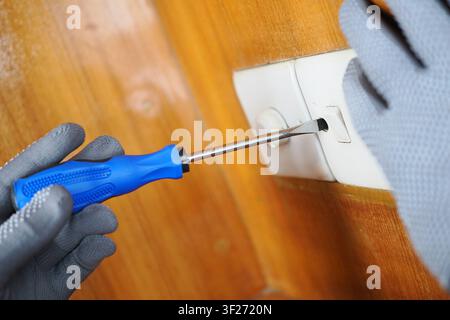 Repairing an electrical outlet with a screwdriver Stock Photo
