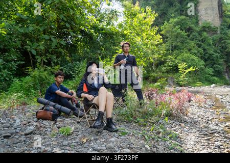 group of young asian men and woman drink from water bottle while resting after trekking and hiking in nature Stock Photo