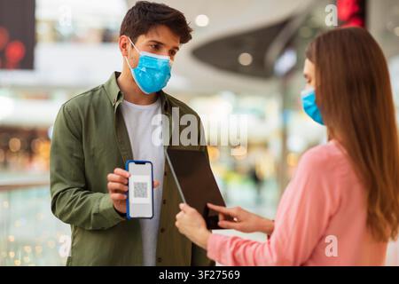 Man And Woman Using Smartphone And Tablet For Digital Payment At Shopping Mall, Business Concept Stock Photo