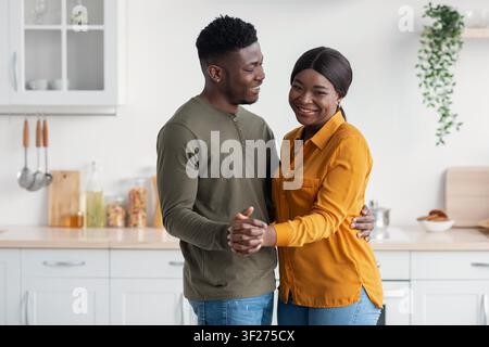Happy Black Couple Dancing Together In Kitchen, Joyful Moment At Home Stock Photo