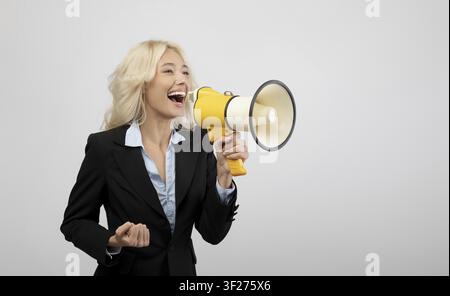 Happy Young Caucasian Woman Using Megaphone, Office Background, Business Concept Stock Photo