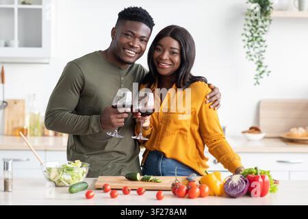 Happy African American Couple Enjoying Red Wine Together In Stylish Kitchen Stock Photo