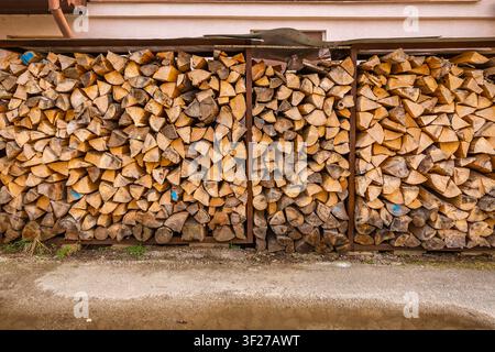 Neatly stacked firewood logs in outdoor storage ready for winter heating season Stock Photo
