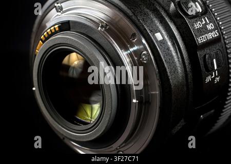 Modern lens on the side of the bayonet on a black background. The lens lens is close-up. Stock Photo