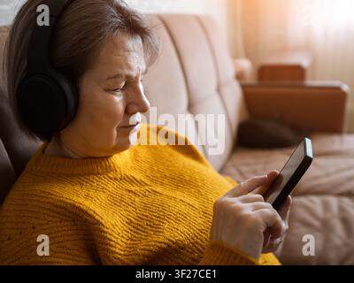 Senior woman relaxing listening to music using smartphone Stock Photo