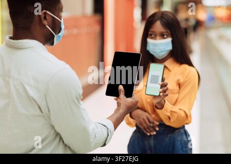 Woman Using Smartphone And Man Holding Tablet In Shopping Mall, Technology Concept Stock Photo