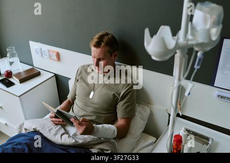 Young Adult Man Recovering in Military Hospital While Reading Book Stock Photo