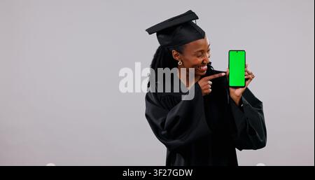 Student, phone and black woman with green screen for graduation app on a white background. Female person, graduate or pointing with smile, technology Stock Photo