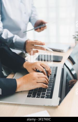 Business team using laptop and digital tablet during office meeting, representing teamwork, business technology, data review and financial planning. Stock Photo