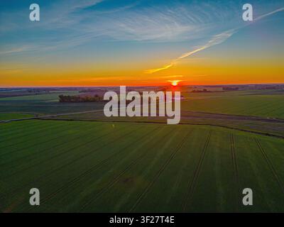 Aerial view of agricultural fields in Jelgava during a vibrant sunset with golden light illuminating the landscape in Jelgava, Latvia. Stock Photo