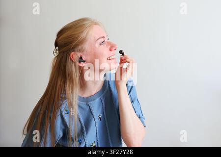 Woman using Bluetooth earphones with charging case, modern technology, communication and everyday convenience concept. Stock Photo