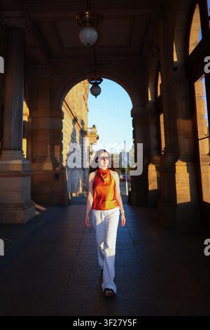 Fashionable young woman in sunglasses exploring a historic city passage at sunset, travel, lifestyle and tourism in Europe. Stock Photo