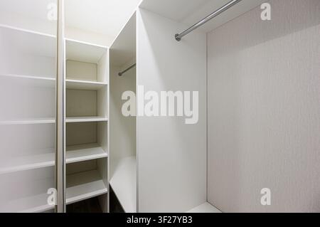 bright, white walk-in closet with shelves and hanging rods Stock Photo