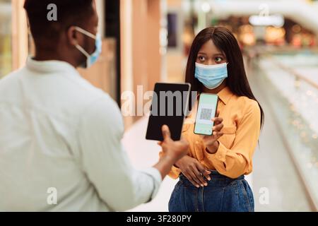 Young Black Woman And Man Using Smartphone And Tablet At Mall, Digital Payment Technology Stock Photo