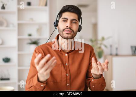 Young Man Wearing Headset Engaging In Online Communication At Home, Business Concept Stock Photo