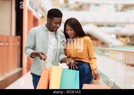 Happy Black Couple Shopping Together With Colorful Shopping Bags At Modern Mall Stock Photo