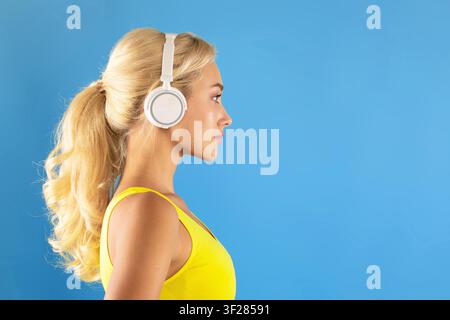 Young Woman Wearing Headphones Listening To Music, Yellow Background, Happy Emotion Stock Photo