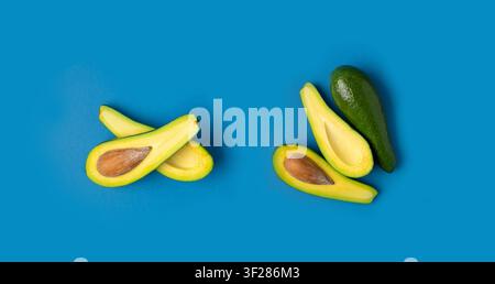 Avocado Isolated, Whole Avokado, Green Avocados Slice, Fresh Alligator Pear, Guacamole Ingredient, Long Avocado Fruit on Blue Background Stock Photo