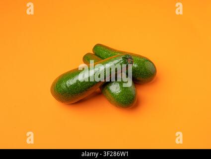 Avocado Isolated, Whole Avokado Set, Three Green Avocados Pile, Fresh Alligator Pear, Guacamole Ingredient, Long Avocado Fruit on Orange Background Stock Photo