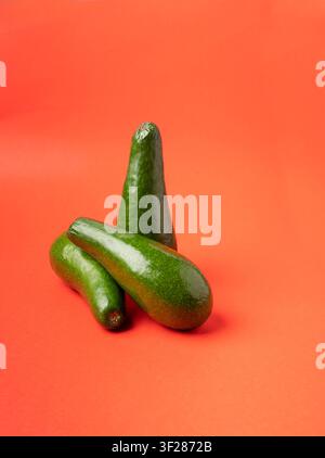 Avocado Isolated, Whole Avokado Set, Three Green Avocados Pile, Fresh Alligator Pear, Guacamole Ingredient, Long Avocado Fruit on Red Background Stock Photo