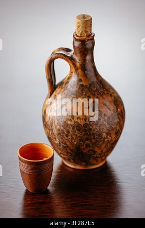 Earthenware jug and cup on a wooden table Stock Photo